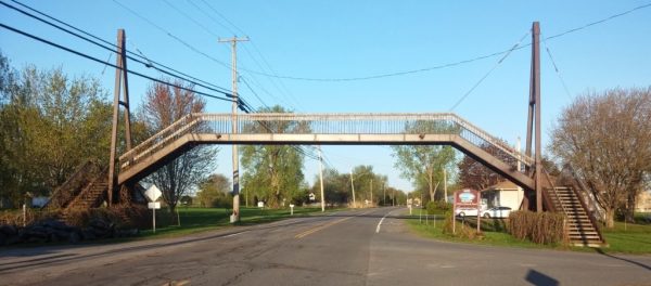 It is hard to find pictures of pedestrian bridges spanning two-lane roads, but picture something like this, but everyone gets to walk up and down long long long wheelchair ramps to cross the street.