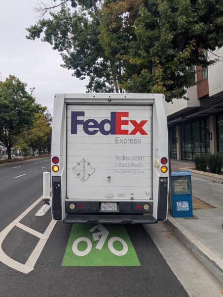 A protected bike lane blocked by a FedEx truck. California license plate 98299Z1