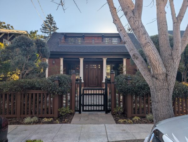 A brown house with patio on the second floor built into the roof line.