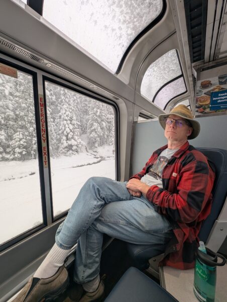 Danny sitting in the observation car, with a view of the snow outside.