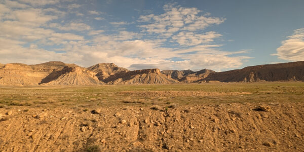 Clouds in the sky above a brown landscape of craggy buttes.