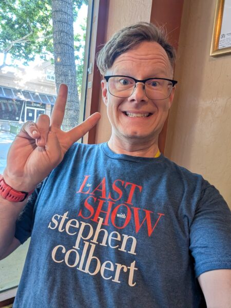 Danny takes a selfie, smiling and flashing a peace sign. He's wearing a "Last Show with Stephen Colbert" tee-shirt.